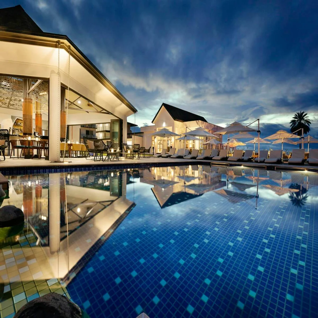 Illuminated tropical resort swimming pool at dusk