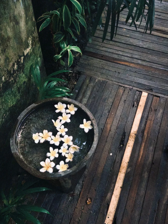 Frangipani flowers in a bowl beside a tropical spa deck